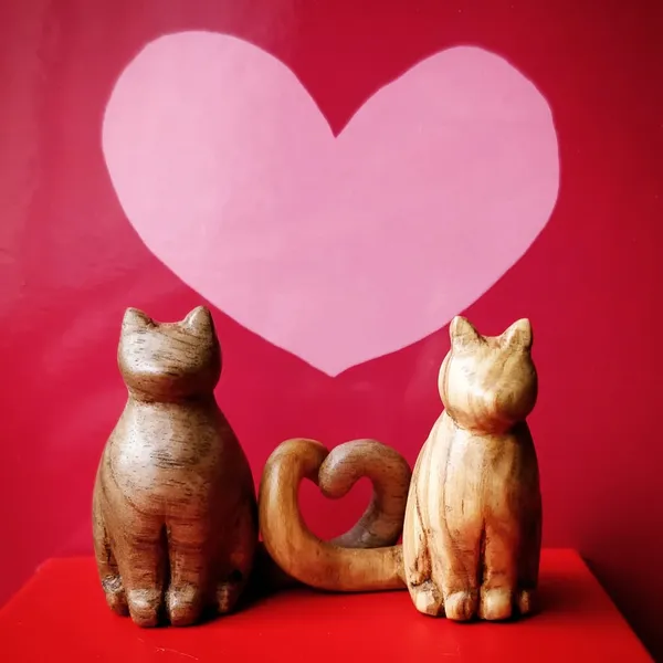 A carving of two cats, their tails make a heart, handcarved from black walnut and olive wood. by Wondiu