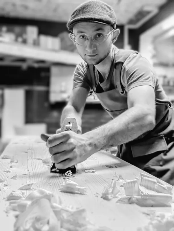 A selfie of Wondiu using a hand plane in their workshop.